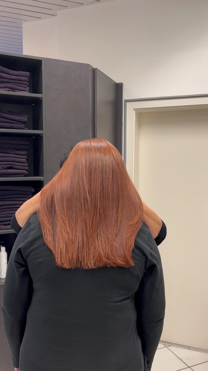 Glänzendes kupferfarbenes Haarfarbenergebnis, Aufnahme von hinten vor dem Regal mit gefalteten Handtüchern